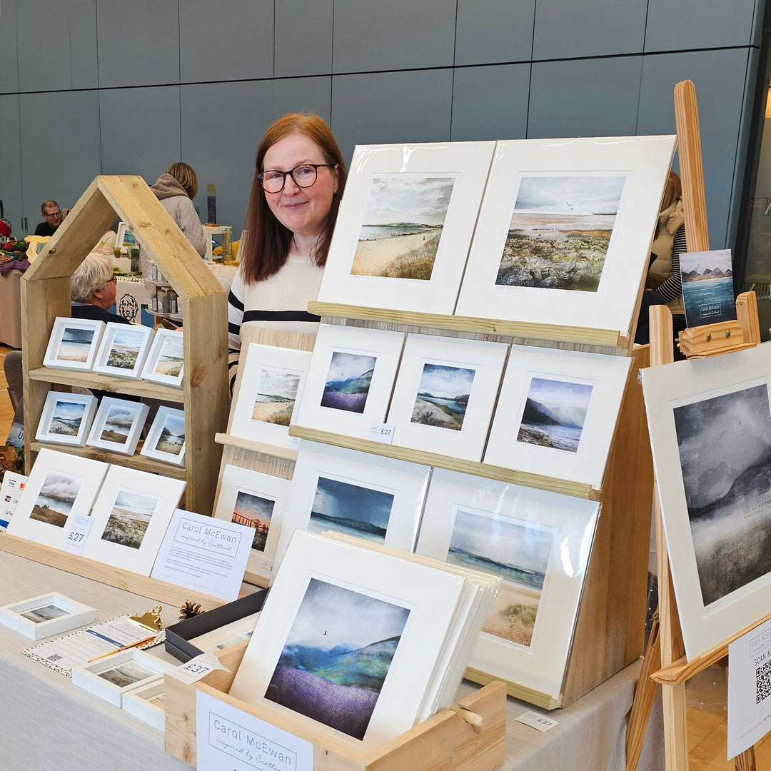 Dundee artist Carol McEwan standing behind her display of prints at a local art fair