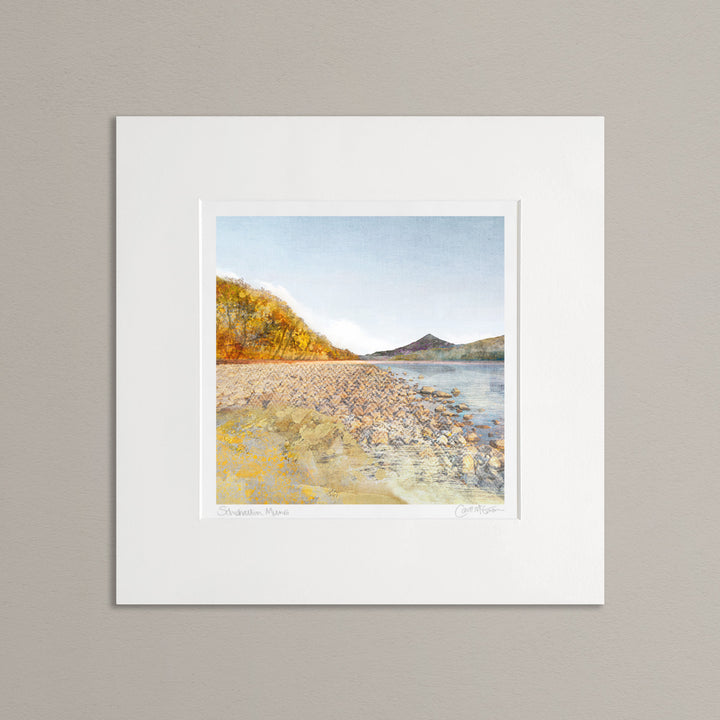 mounted print of Scottish mountain Schiehallion in the distance, viewed from Loch Rannoch. The trees on the left are a golden colour and in the foreground is a rocky loch shore.